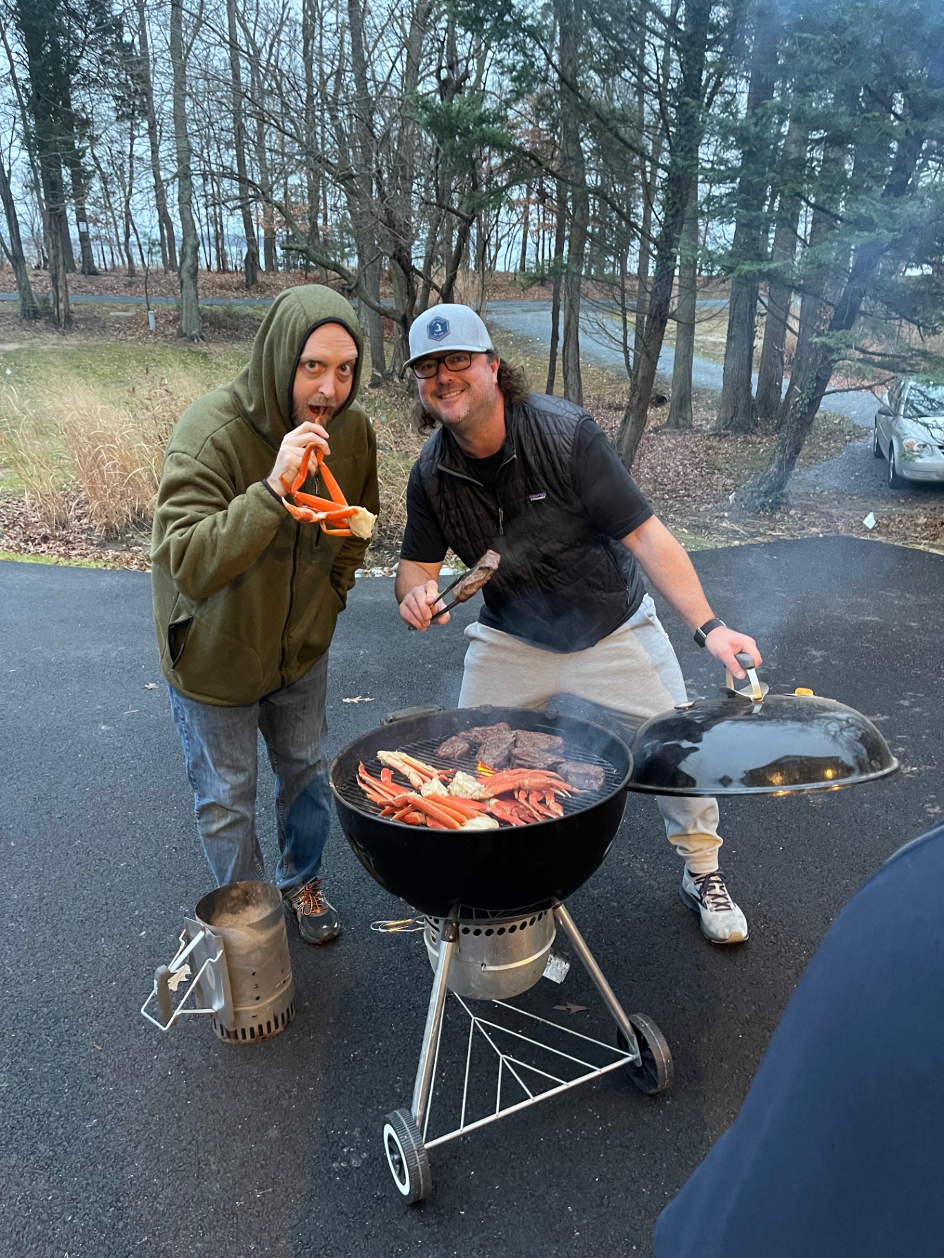 Two friends cooking crab legs and steaks over charcoal