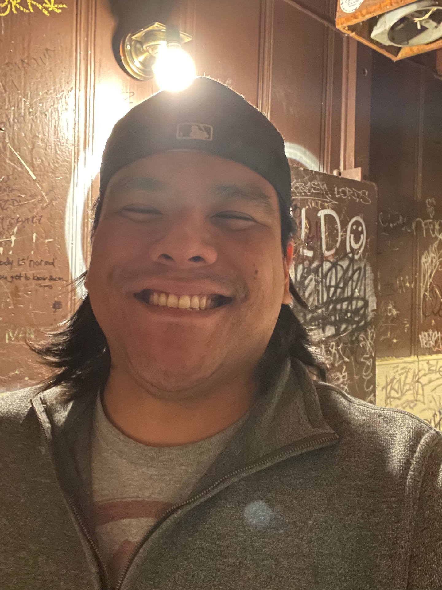 A smiling friend in a room with graffiti-covered walls