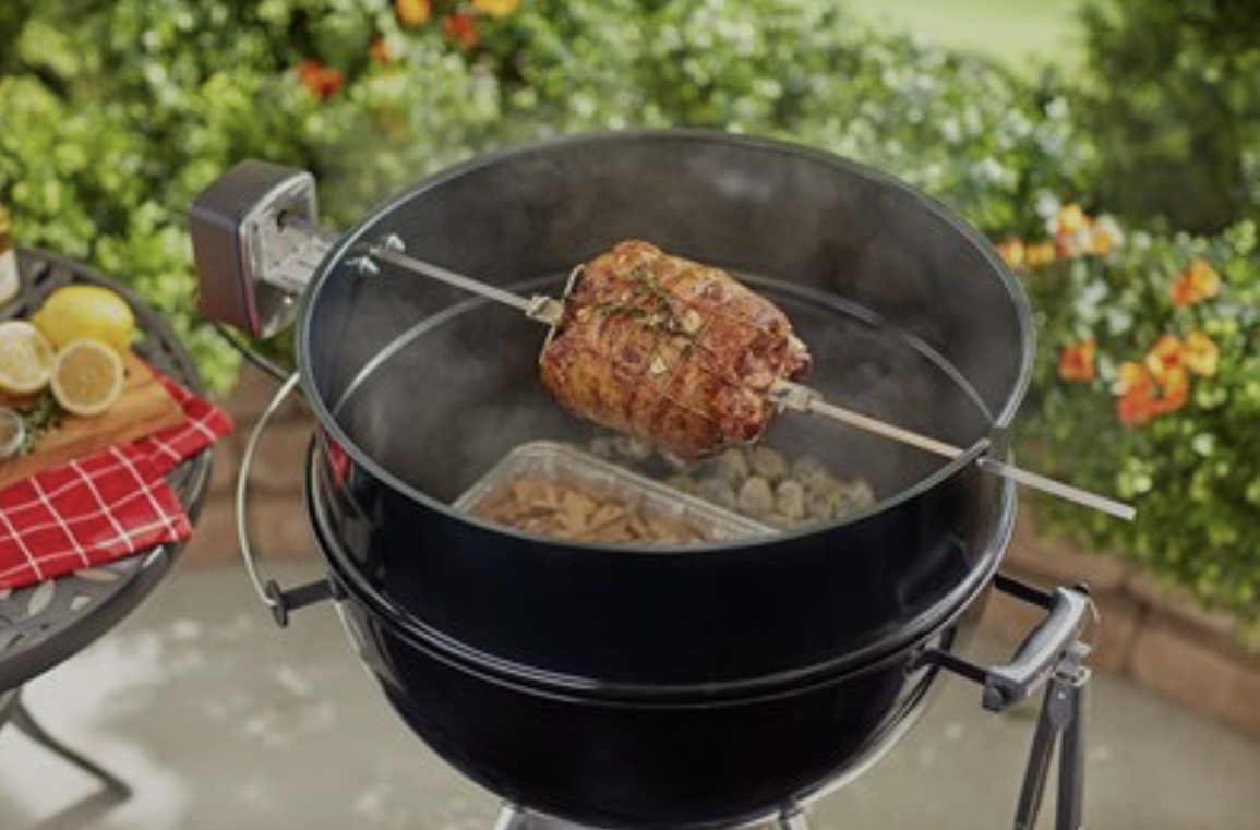 A whole roast turning on a rotisserie over charcoal