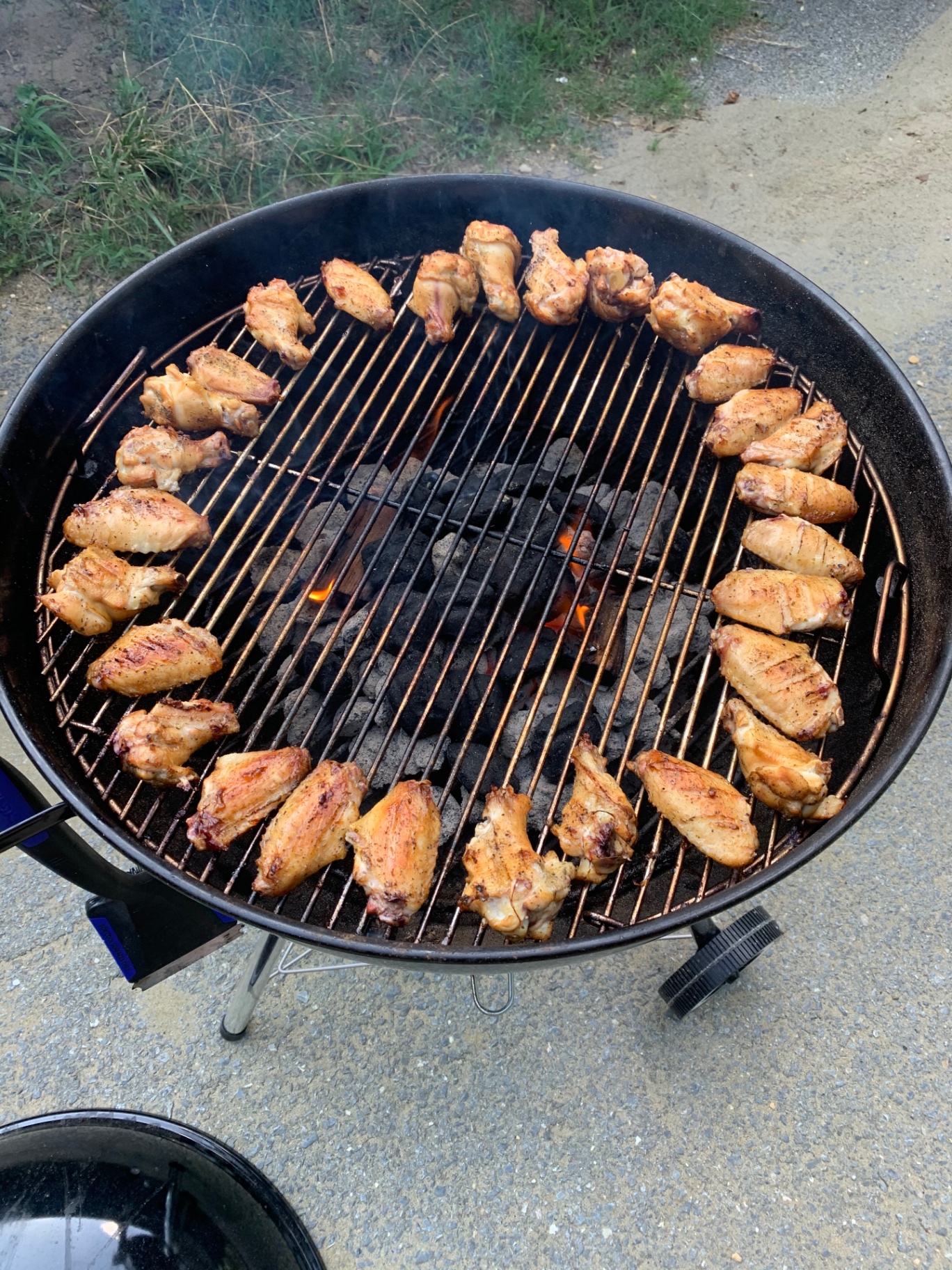 Chicken wings arranged in a ring on a charcoal grill