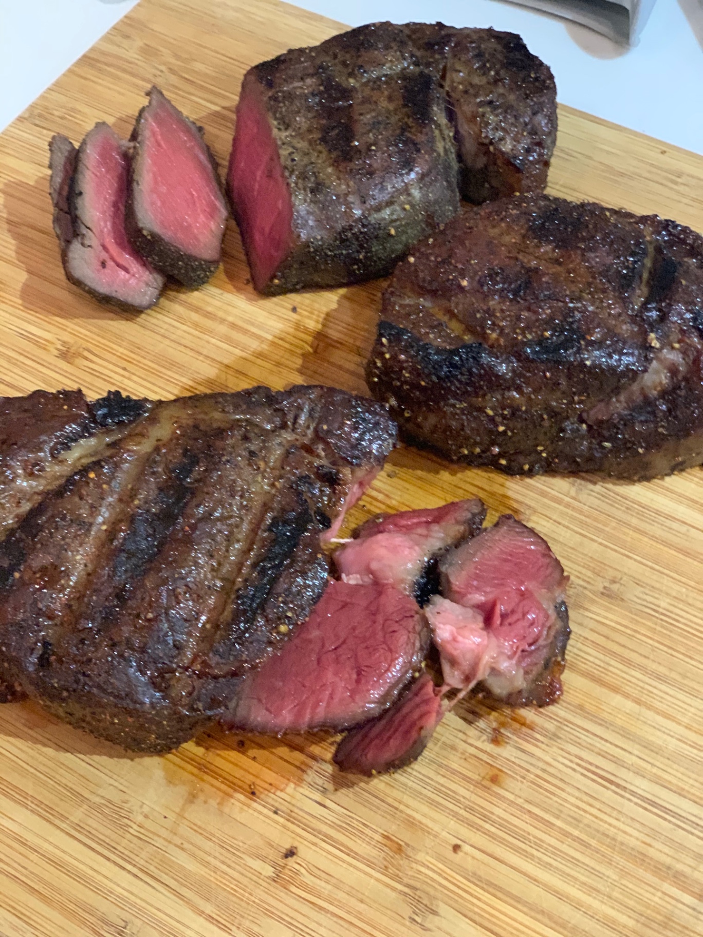 Sliced medium-rare steaks resting on a cutting board