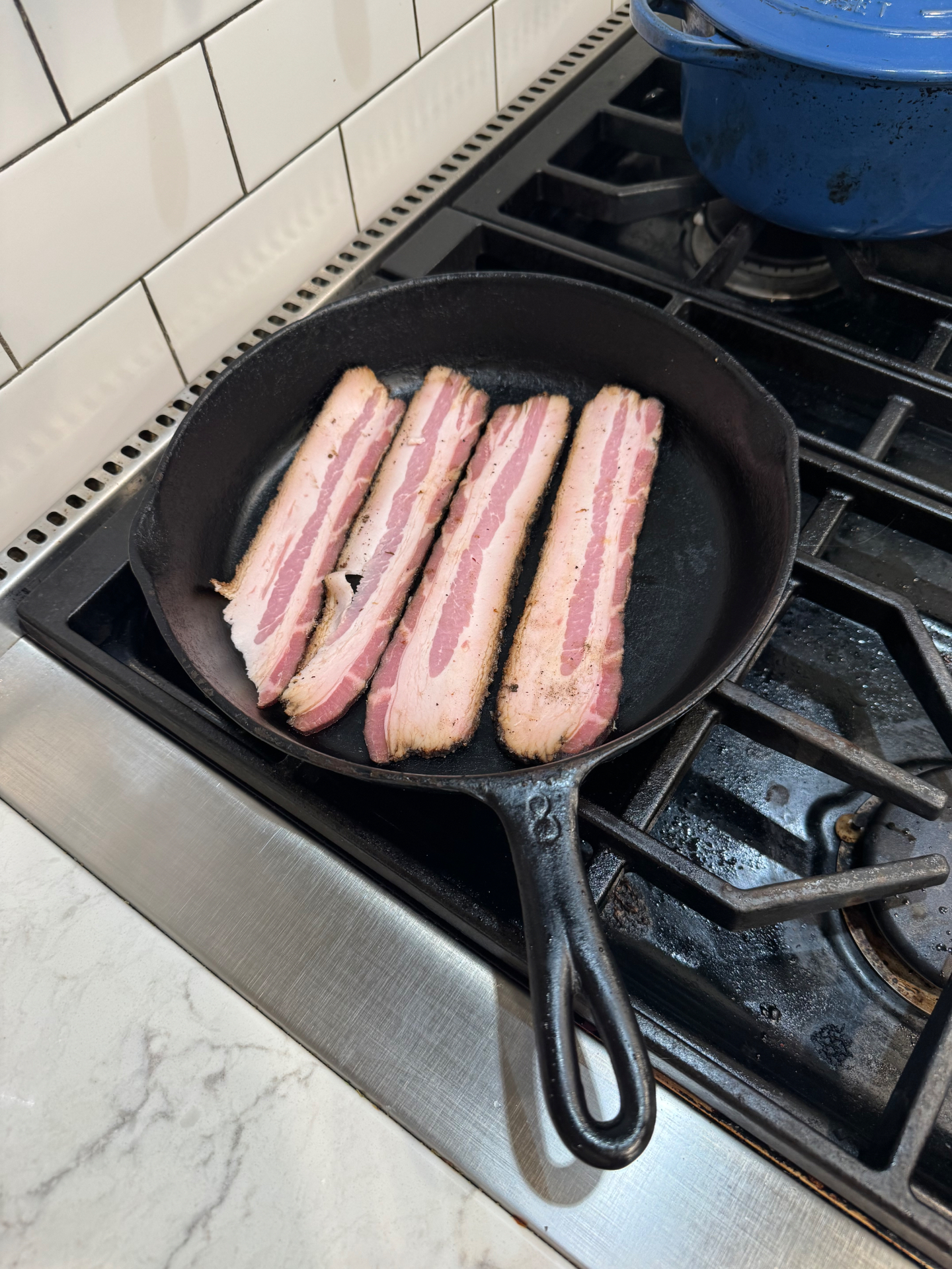 Four thick-cut bacon slices laid in a cast iron skillet