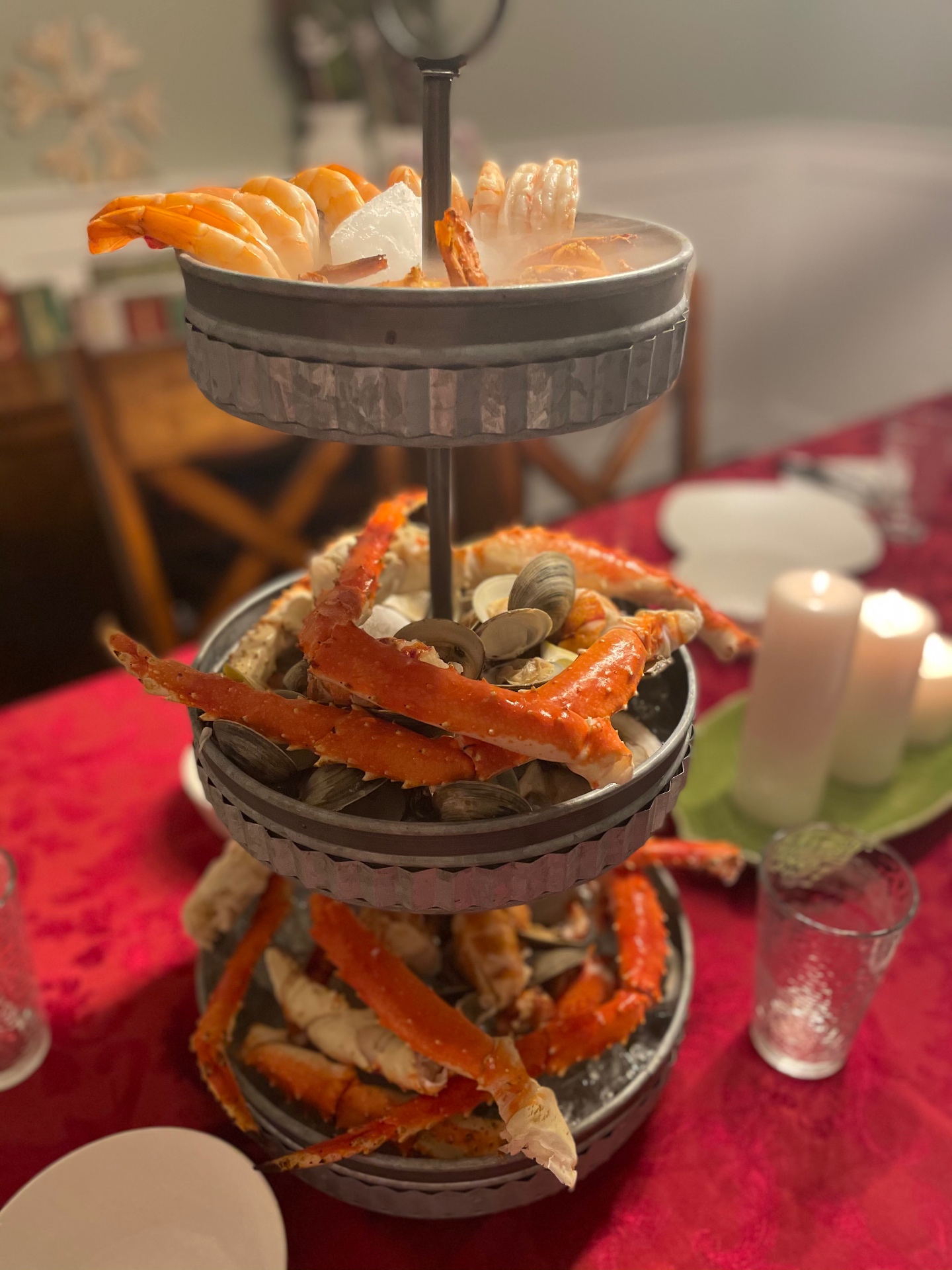 A three-tier serving stand piled with crab legs, clams, and shrimp