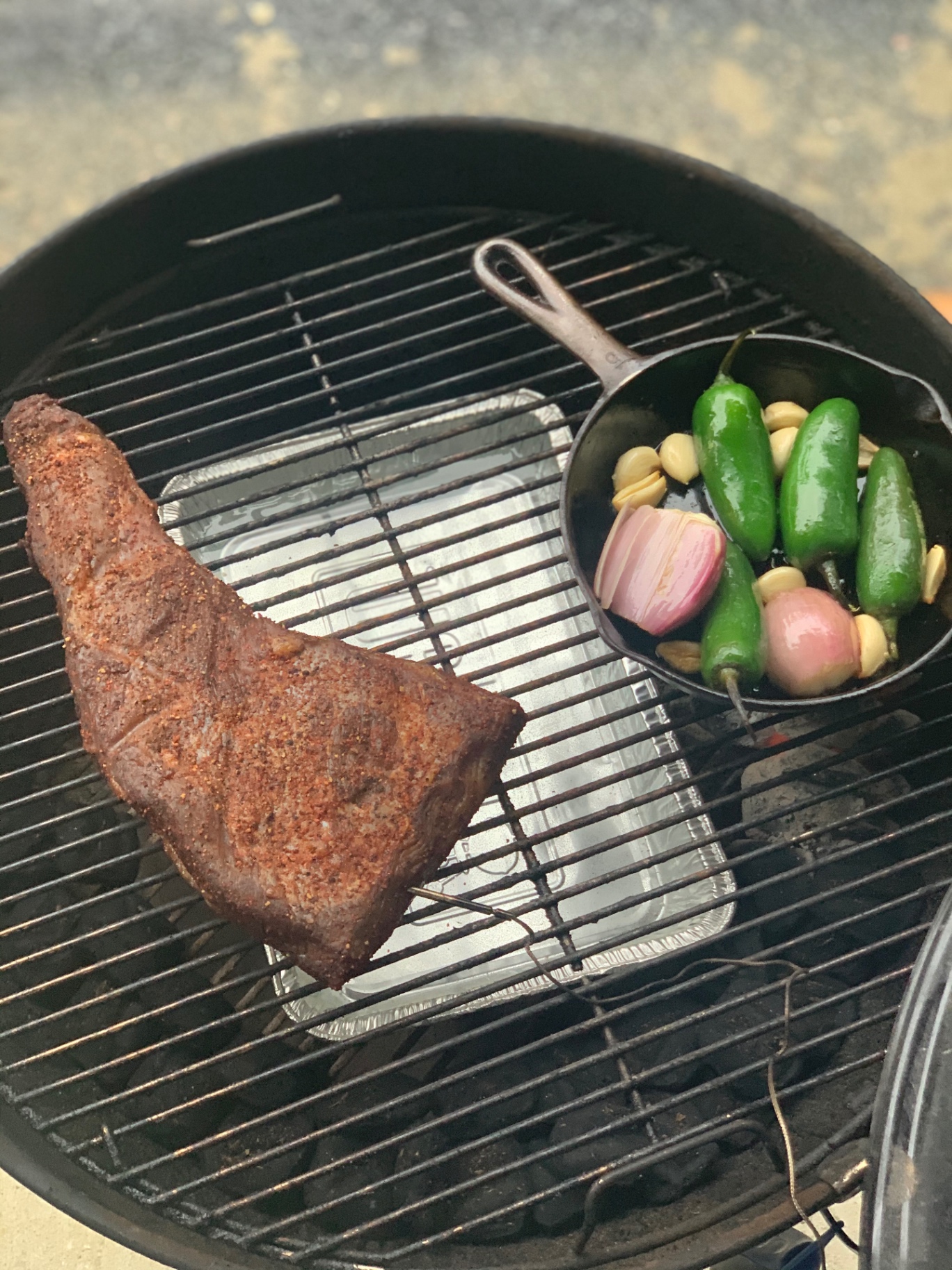 A smoked steak beside a skillet of peppers and onions