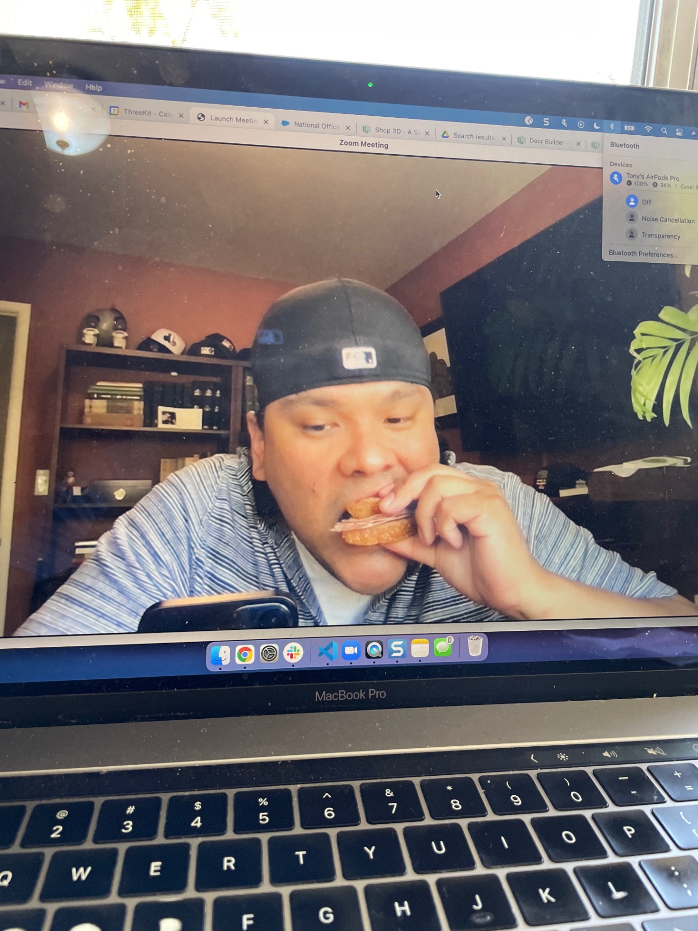 A video call participant enjoying a ham sandwich on screen