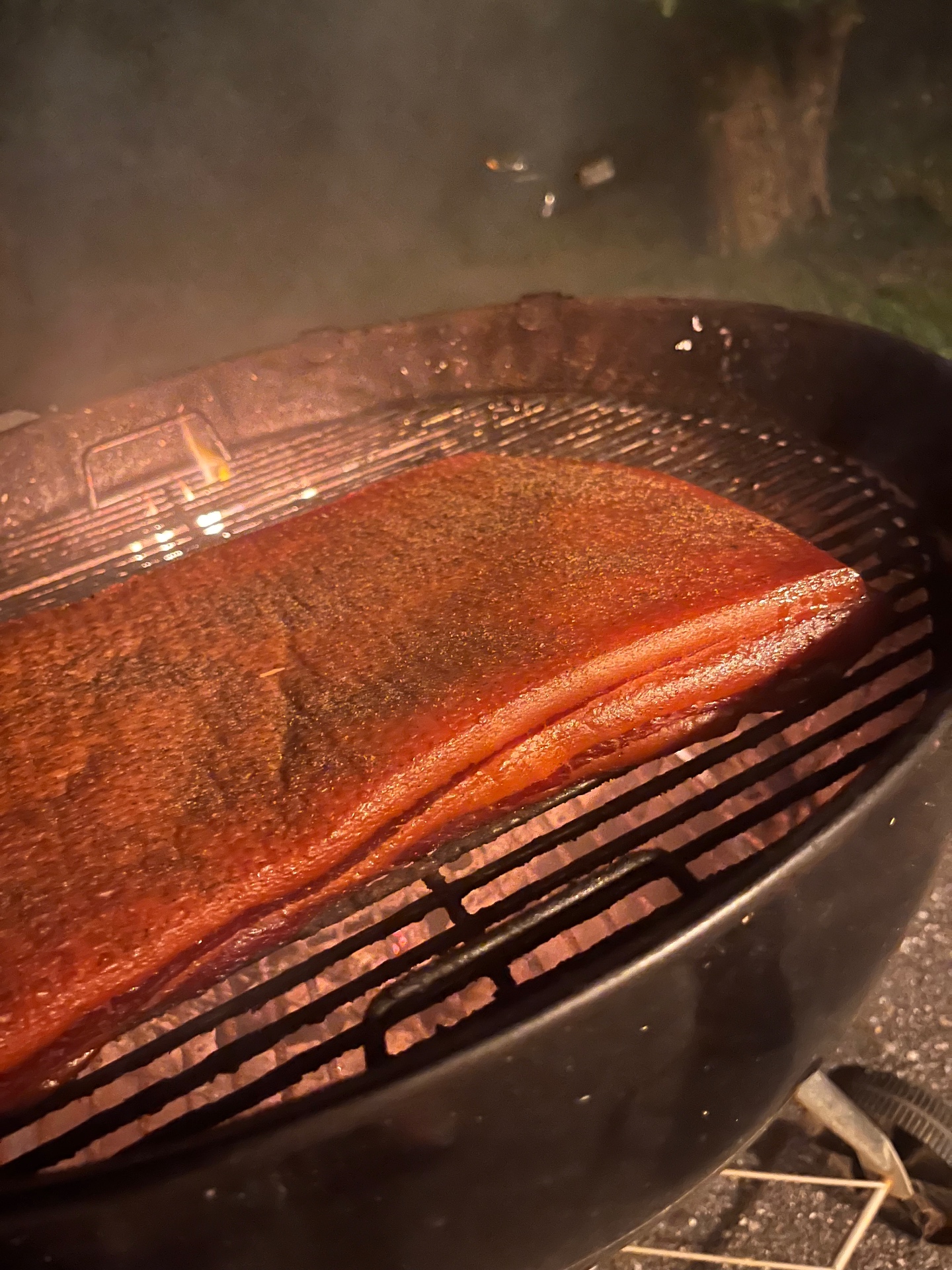 Close-up of the cured pork belly on the Weber grate taking on smoke color